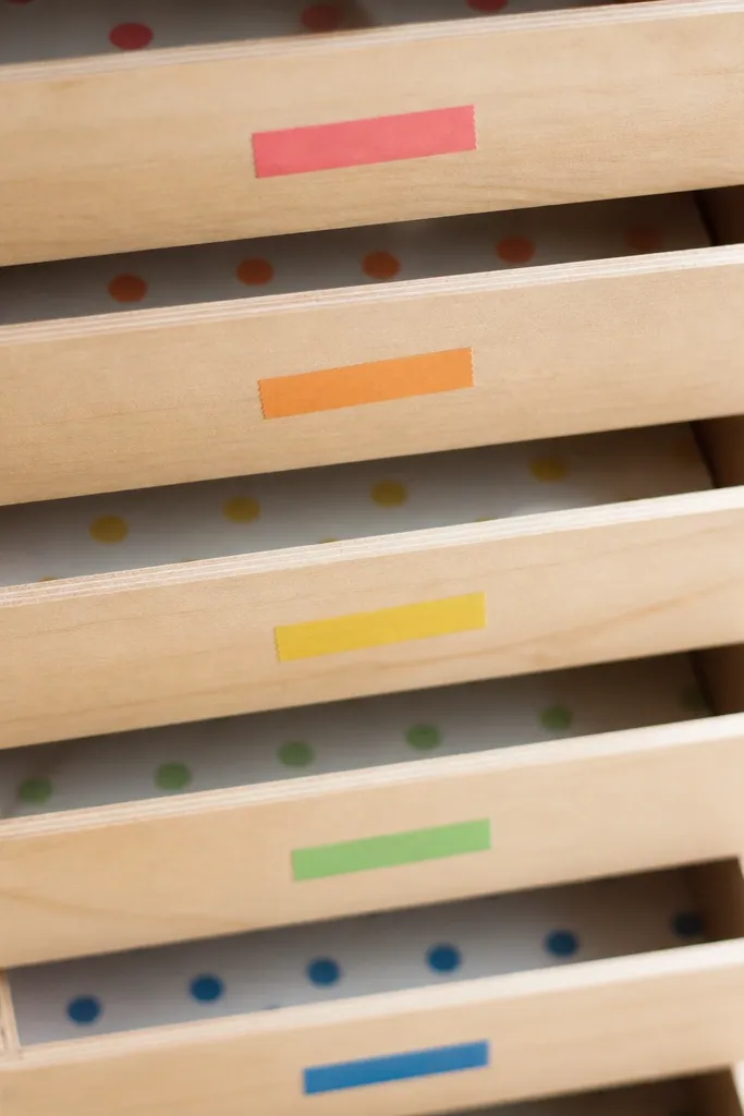 Close-up of drawer fronts with small washi tape strips in different colors and matching dots inside each drawer.