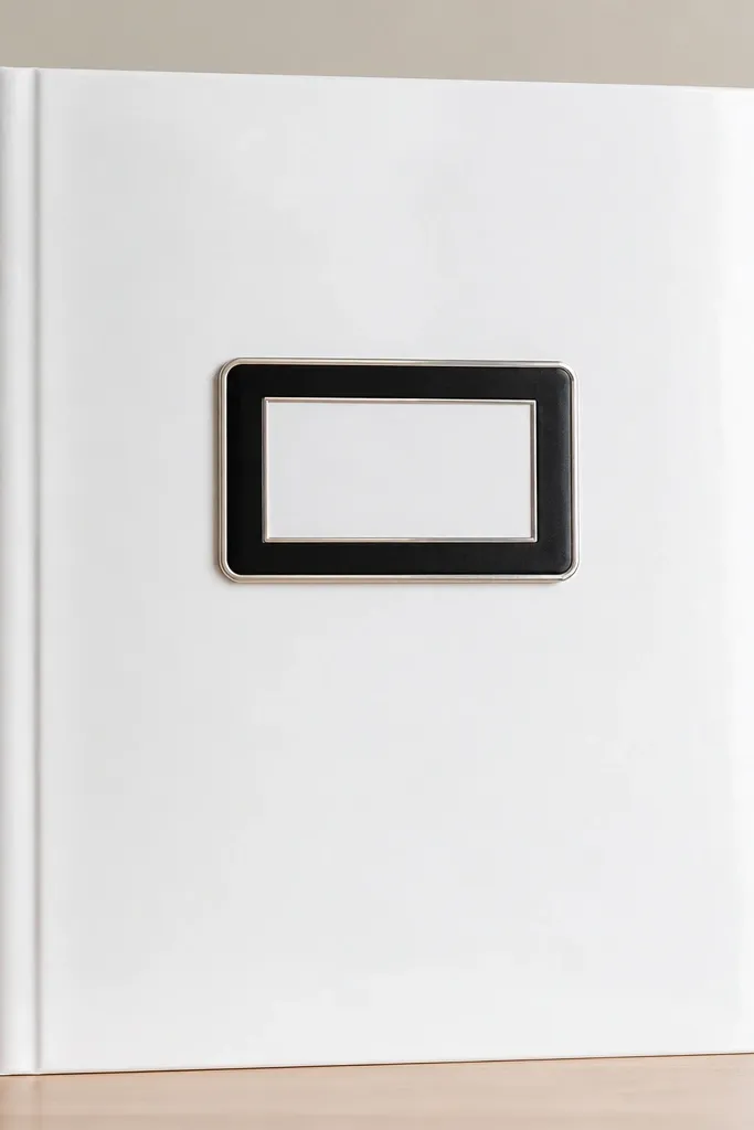 A clean white scrapbook cover using glossy photo paper, with a black acrylic-looking nameplate centered. The nameplate has a crisp printed label inside and a thin silver border. The corners are rounded and the spine is straight.