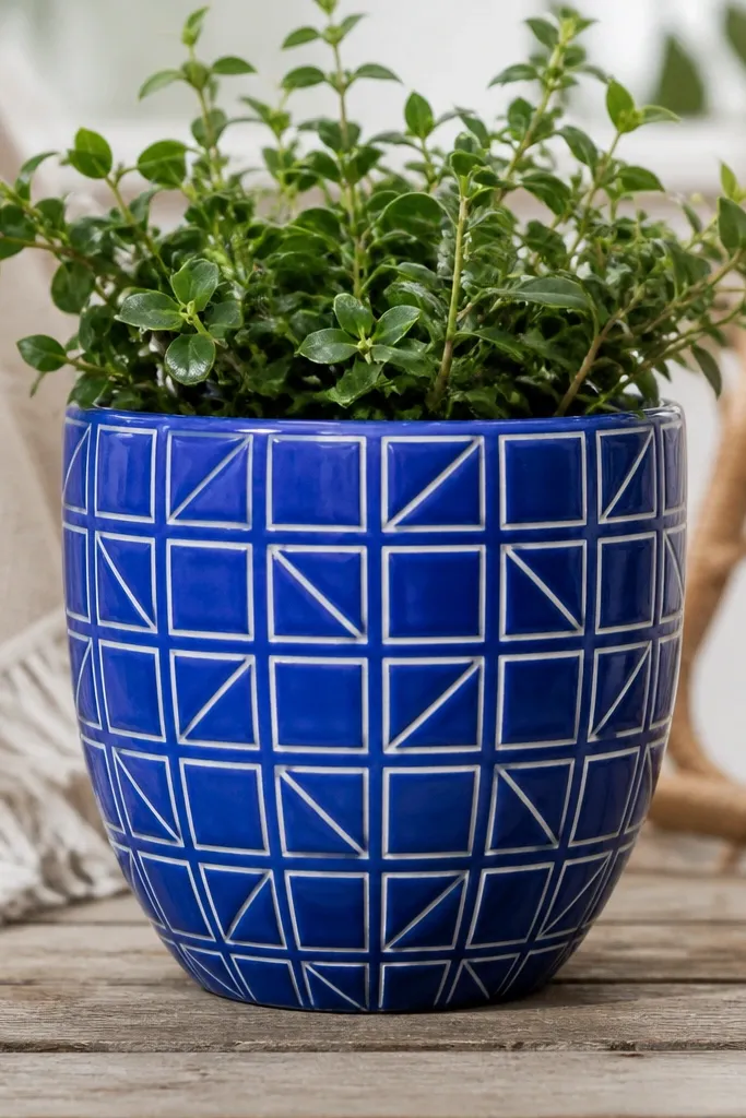 A cobalt blue pot with white outlined geometric tile shapes, like small squares and triangles, arranged in a repeating pattern.
