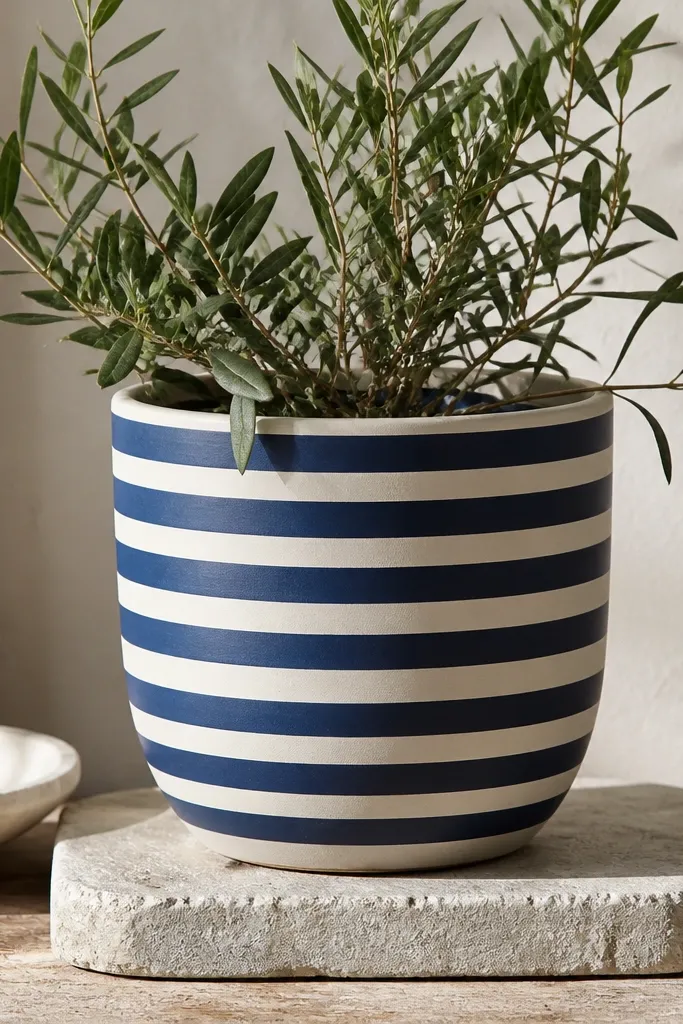 A pot painted with navy and cream horizontal stripes, wrapped around the full circumference with consistent spacing.