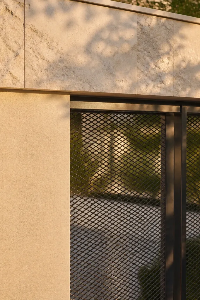 Limestone-look wall top with mesh gate and sturdy pillars