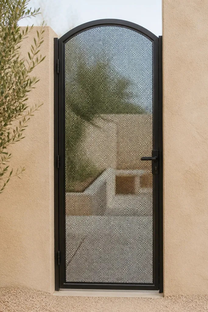 Sandstone-textured wall with arched mesh gate in a black metal frame
