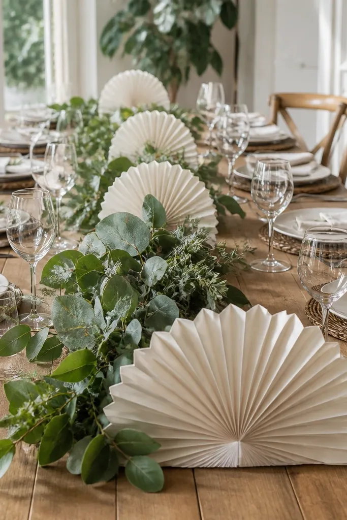 Cream paper fan decorations at runner ends with a small greenery bundle centered