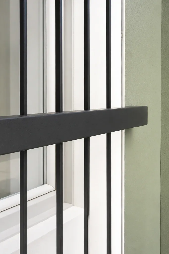 Black window grill with slim vertical bars and a thicker horizontal band across the middle