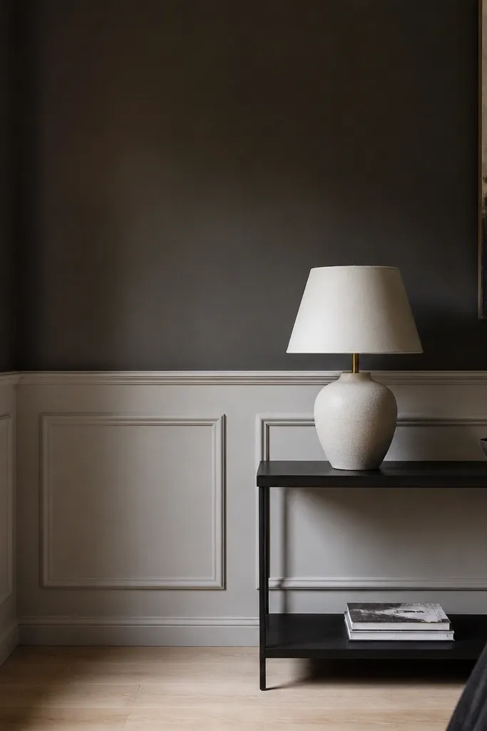 Greige half-wall with white panel molding and a charcoal accent behind the sofa