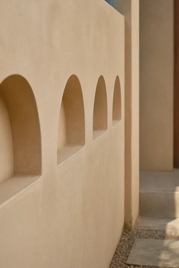 Wall with repeating half-moon recesses and a light sand-colored finish
