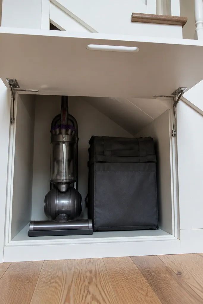 Lift-up top cabinet under stairs with vacuum stored inside