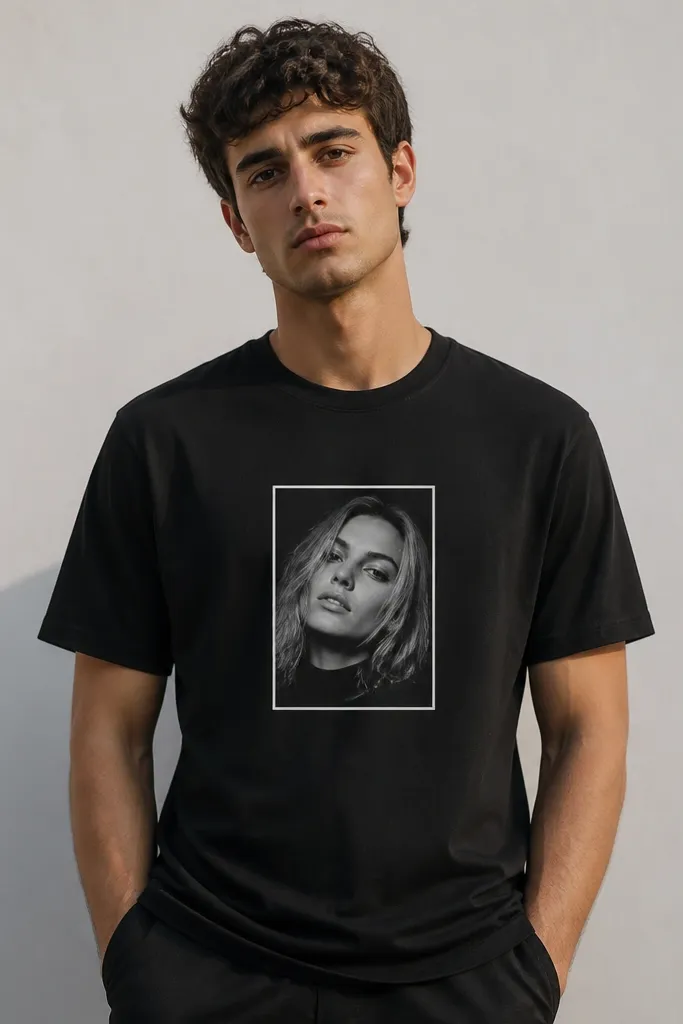 A simple black t-shirt with a small printed portrait photo on the chest, framed by a white rectangle. The print looks crisp and centered with clean edges.