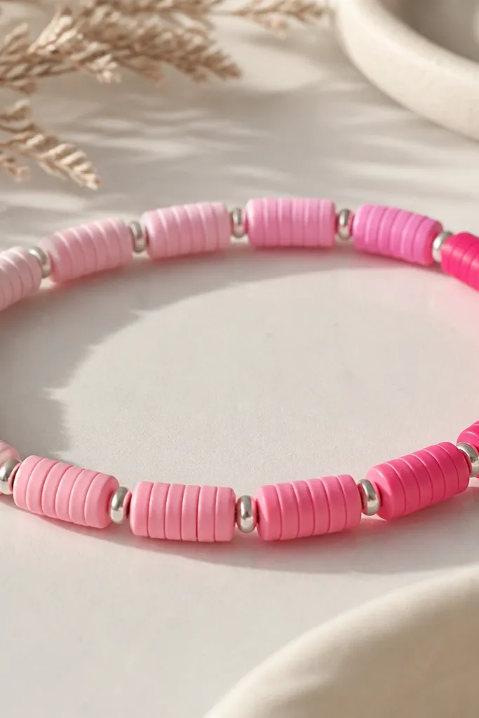 Clay beads that fade from pale pink to hot pink in order along the bracelet, separated by tiny silver spacer beads.