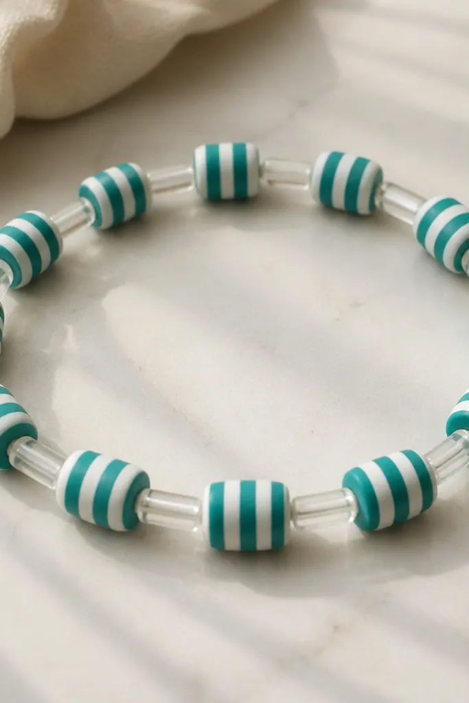 Striped teal-and-white clay beads alternating with small clear plastic tube separators along the bracelet.