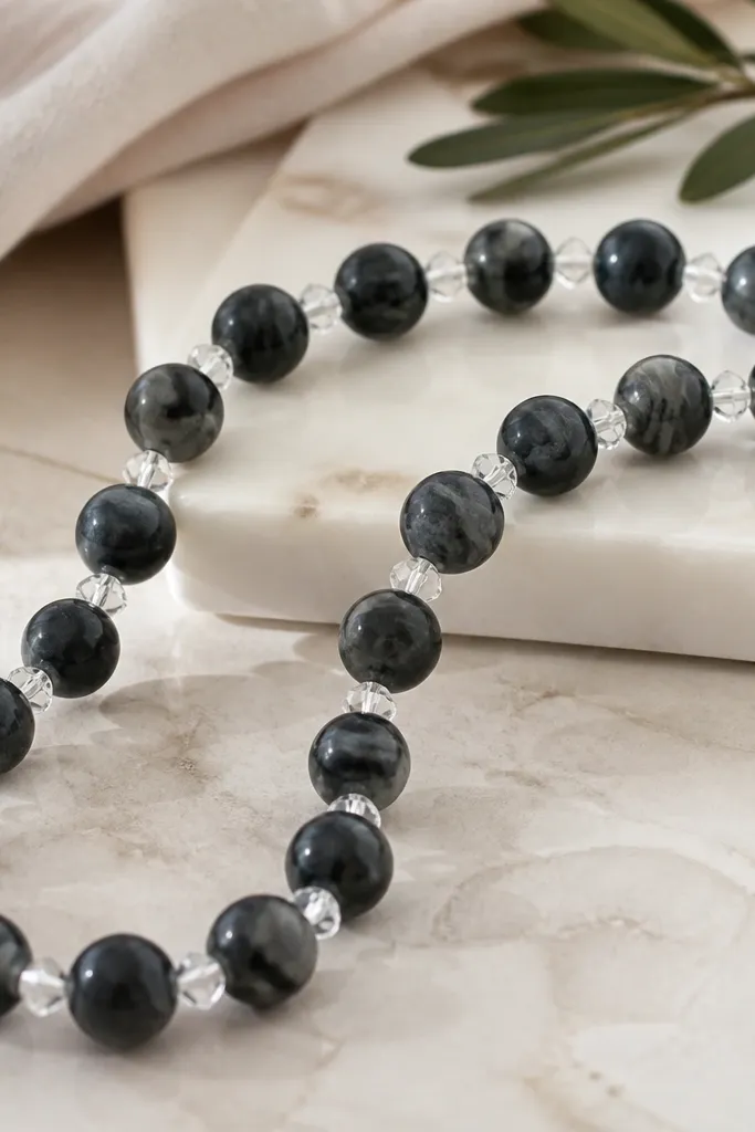 Black marble clay beads with gray swirls, spaced by small clear crystal-like beads that look faceted.