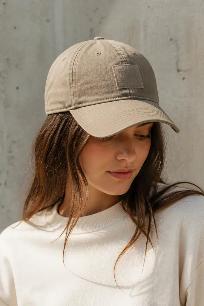 A baseball cap has a small fabric patch on the front with clean stitching around the edges; the patch matches the cap color scheme.