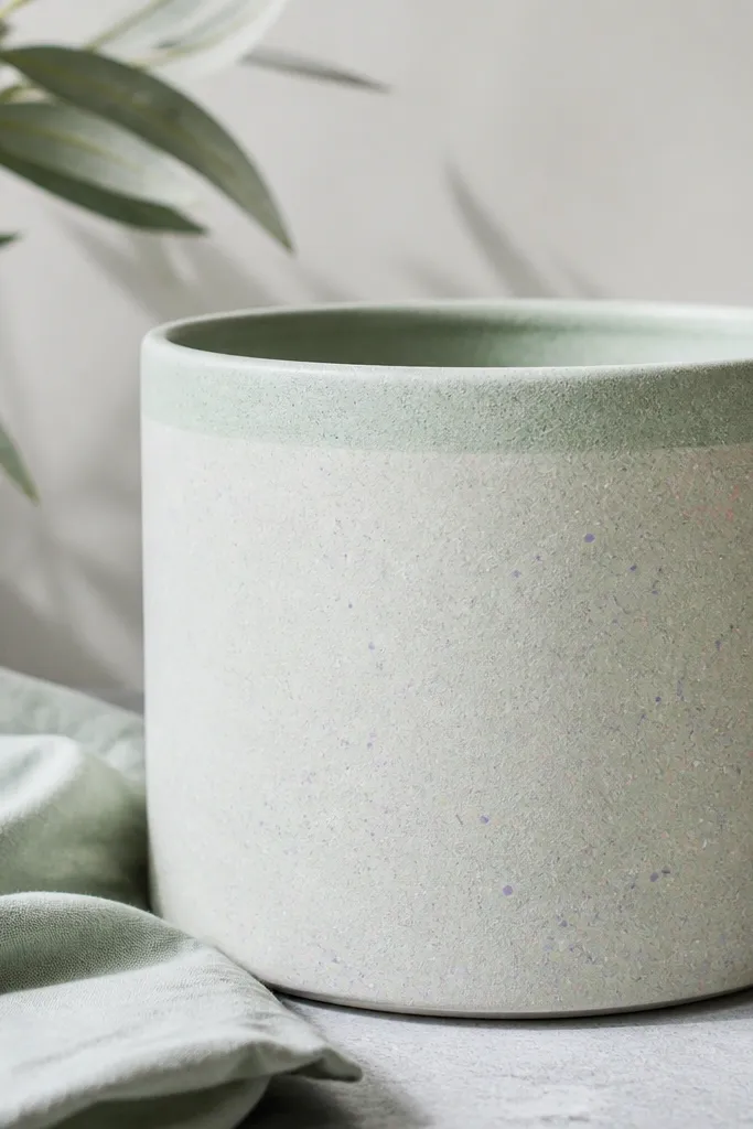 A pale mint pot with speckled flecks of pink, lavender, and white across the surface, with a slightly darker mint ring around the top.