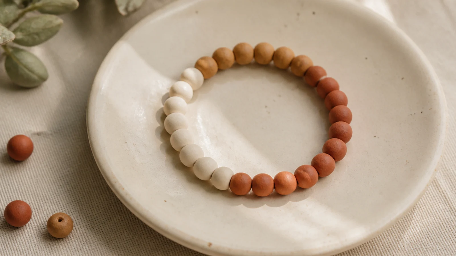 A clay bead bracelet in three clean blocks of cream, camel, and terracotta around the band.