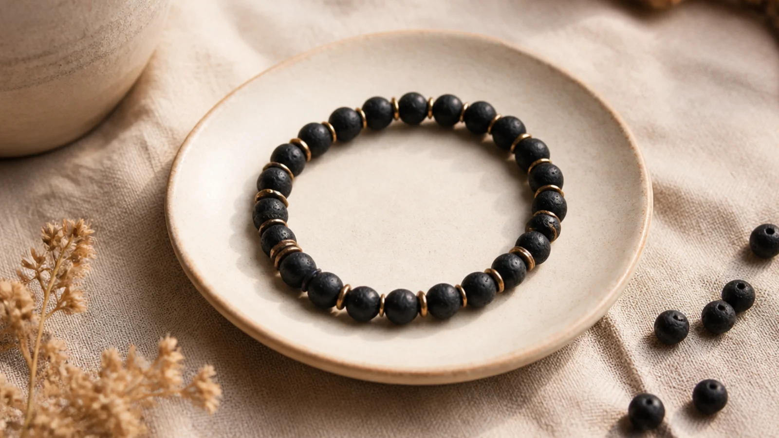 A black clay bead bracelet with matte gold or gunmetal spacers placed evenly throughout.