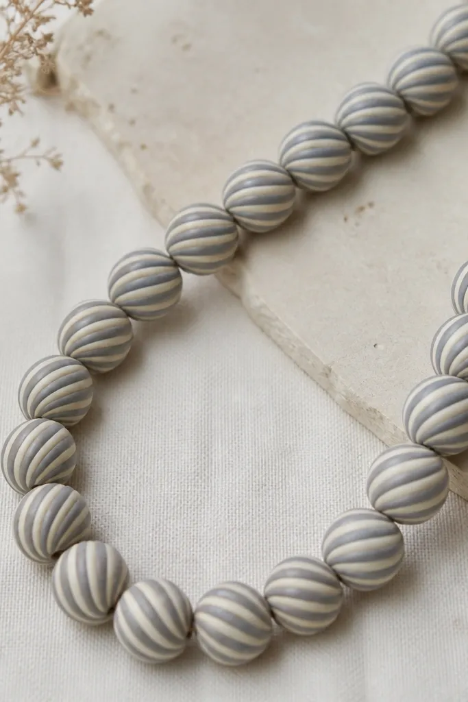Beads with a twist pattern - alternating cream and muted gray stripes spiraling around each bead; the seam is hidden on the back side.