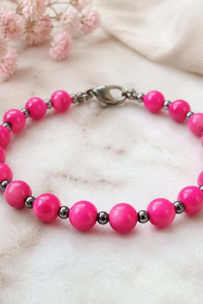 A bright hot pink bracelet with glossy-looking hot pink clay beads (6mm) spaced by small dark gray metal-like beads (about 3mm). The bracelet has a dark silver clasp and the front looks uniform.