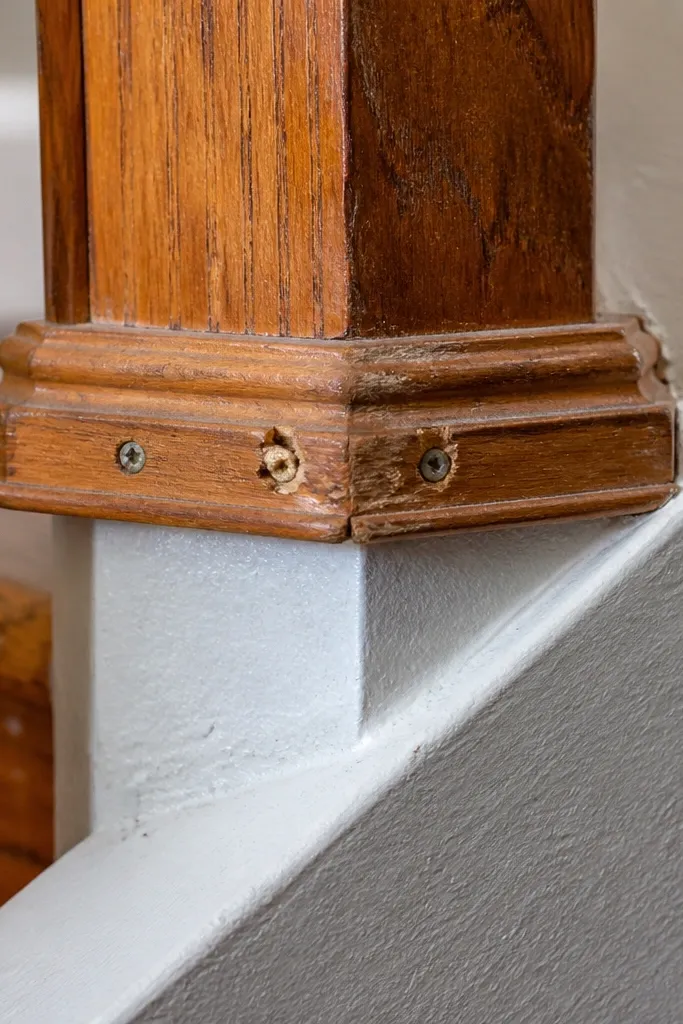 screws next to a wooden post and a concrete bracket