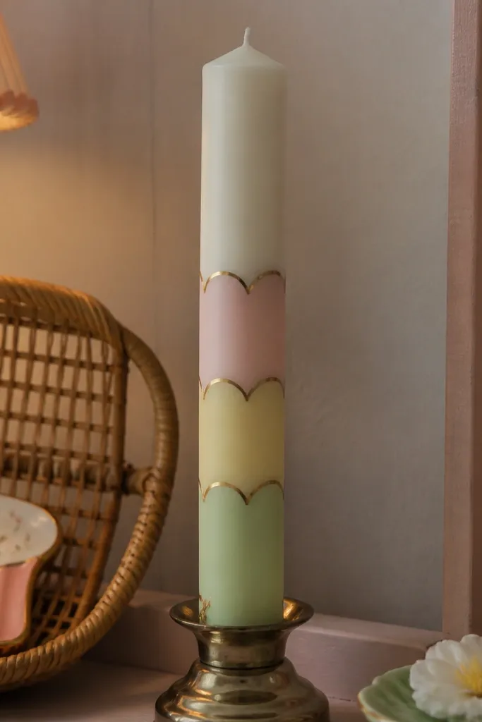 White candle with scalloped pastel bands and thin gold edges