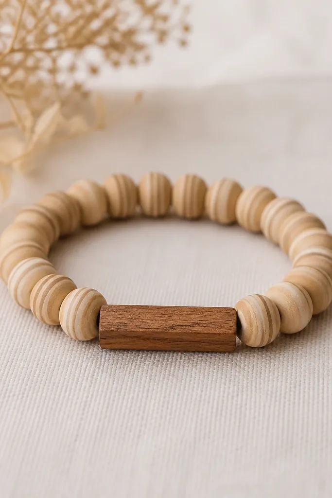A bracelet made of light beige and tan striped clay beads, with a single small rectangular wood bar bead in the middle; the bracelet looks warm and matte.
