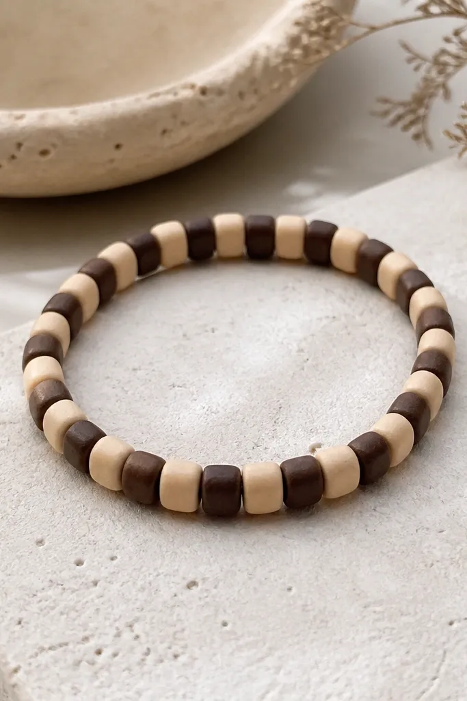 A checker pattern bracelet made of alternating light and dark clay beads, each bead with slightly rounded edges, laid out in a clean repeating grid look.