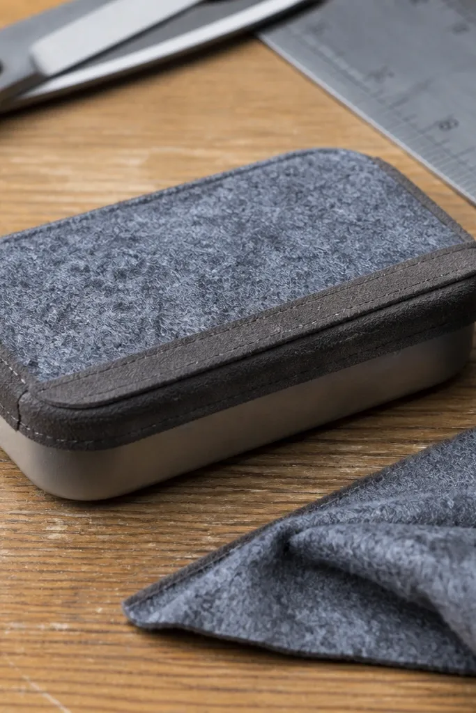 Olive felt Altoids wallet with a thin brown binding strip on the outer edge
