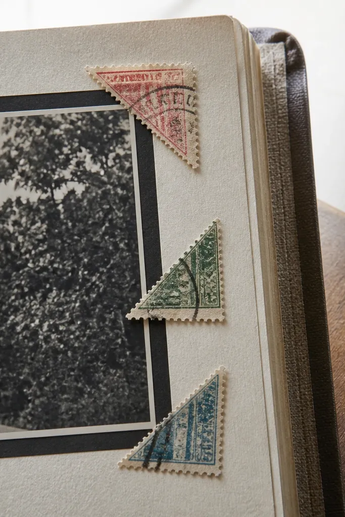 Three worn postage corner stickers in warm cream and faded brown