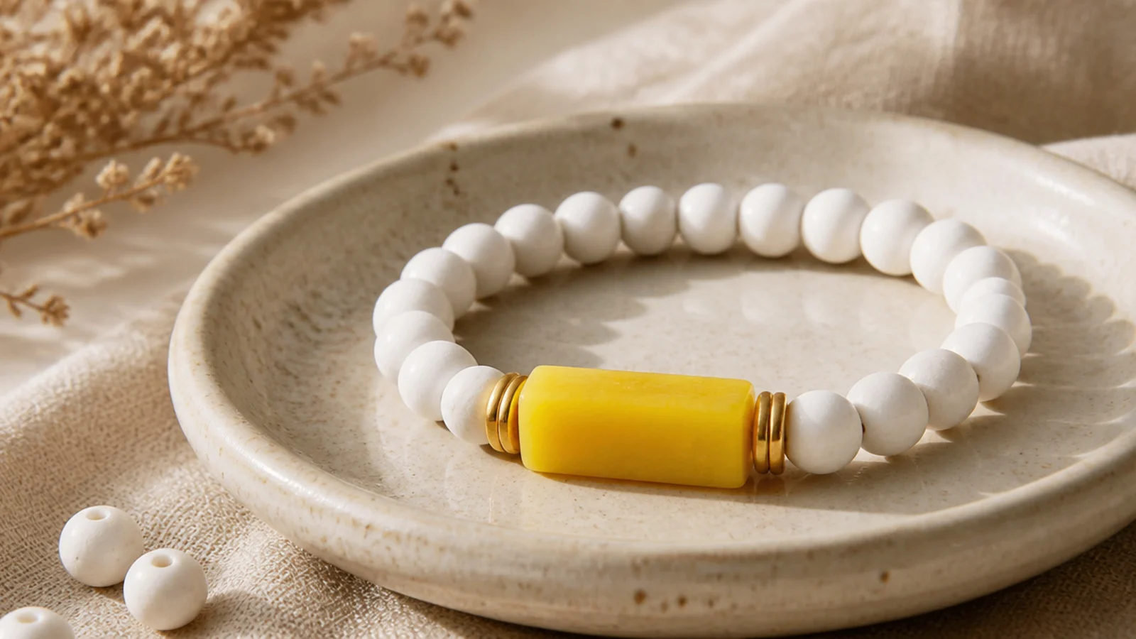 A bracelet with a bright lemon-yellow block on the front and white clay beads wrapping the rest of the band.