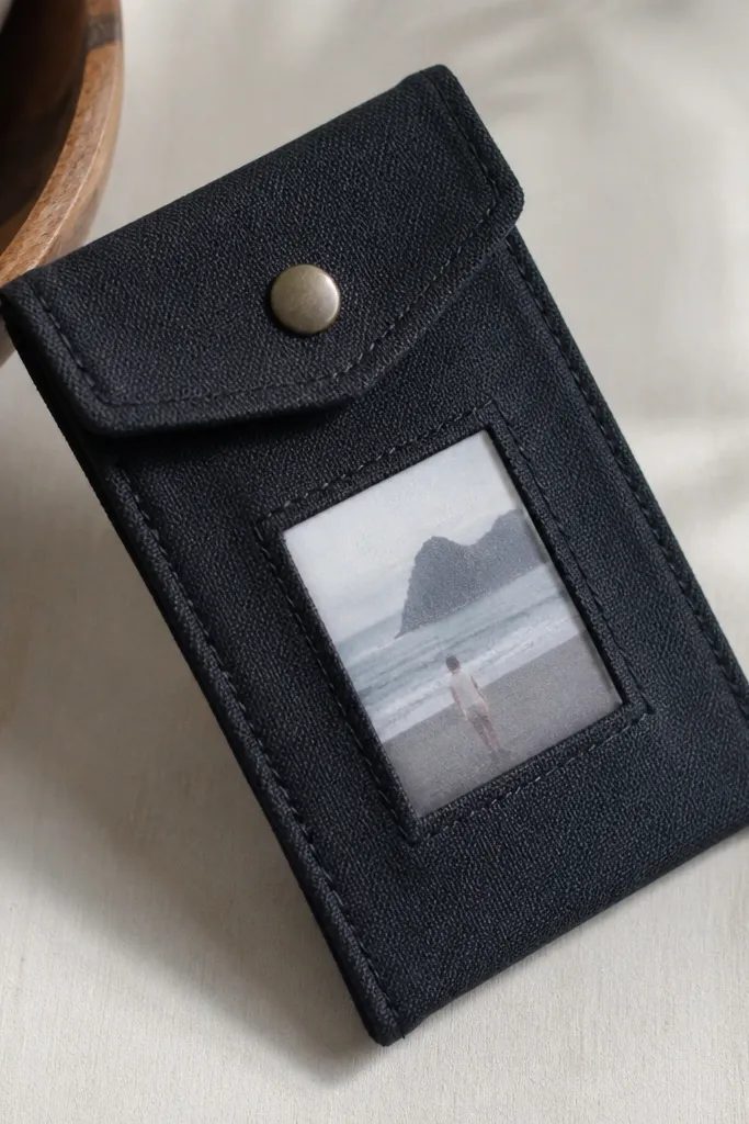 A slim fabric pouch made from dark canvas with a small clear window showing a mini photo, stitched-looking edges created with fabric glue, and a simple snap closure.