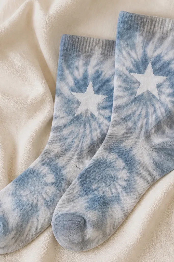 A pair of socks with a soft tie-dye swirl in muted blue and gray, with a crisp white star stencil centered on the ankle.
