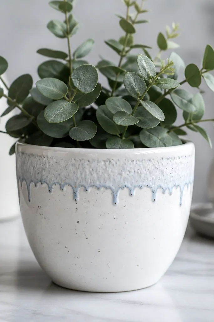 A white pot with a snowy top band and small blue drips hanging down from the band, plus tiny silver speckles.