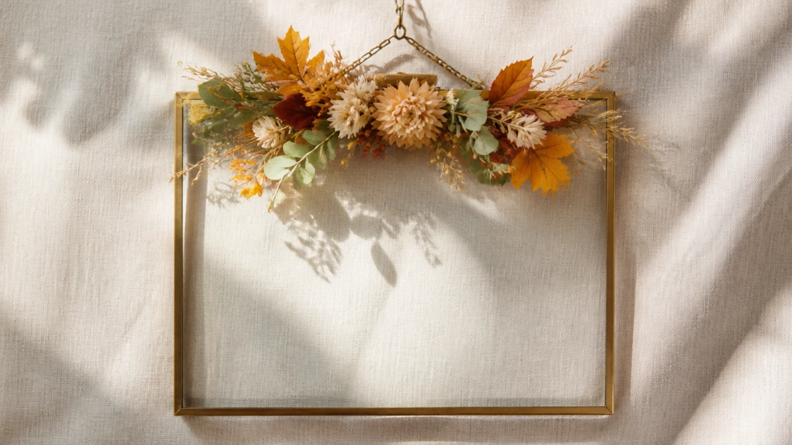 An empty frame with a removable seasonal floral swag clipped to the top, shown with autumn leaves and blooms.