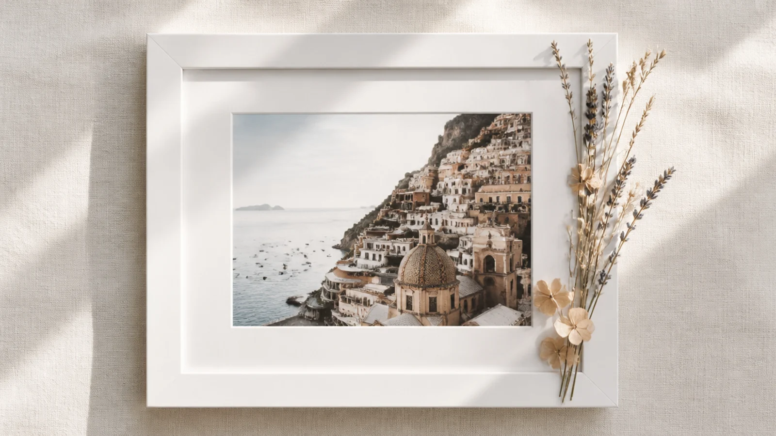 A plain white photo frame with a small cluster of dried flowers glued to one corner, the photo clearly visible.