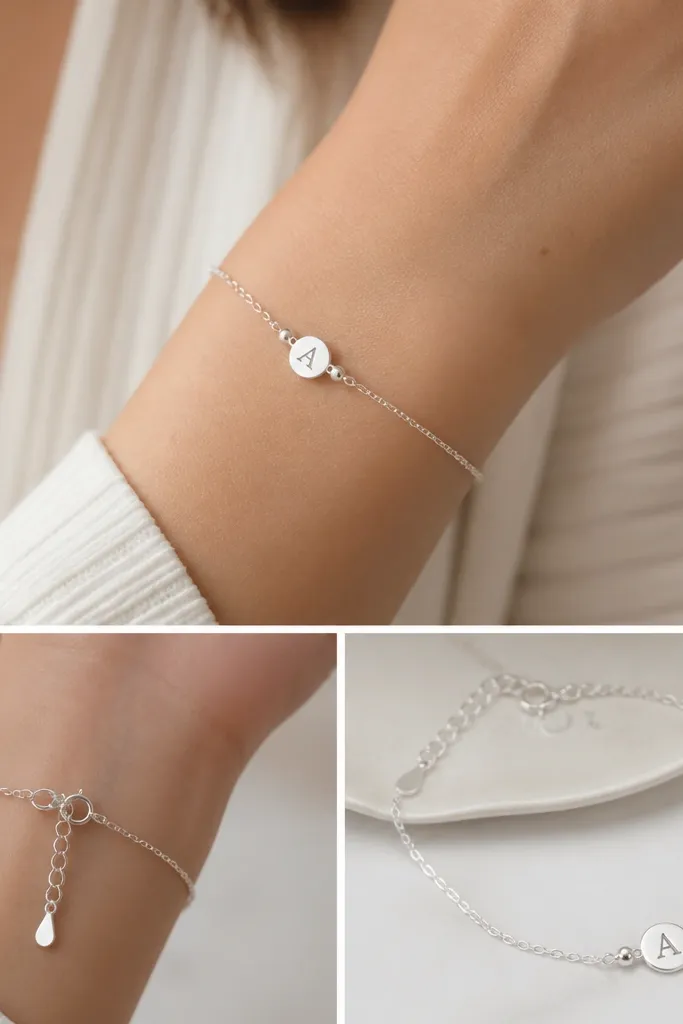 A close-up of a dainty silver bracelet with a small initial charm centered on the wrist, plus two tiny spacer beads; the clasp is clearly shown as an adjustable extender chain.