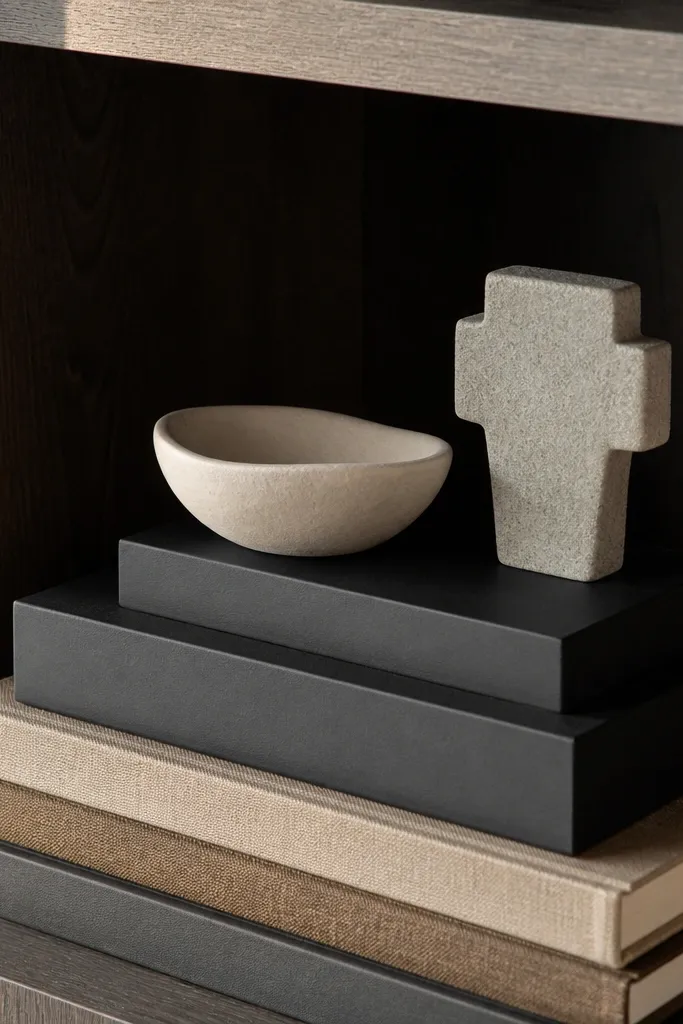 Built-in shelves with matte black risers, layered books, and small sculptures