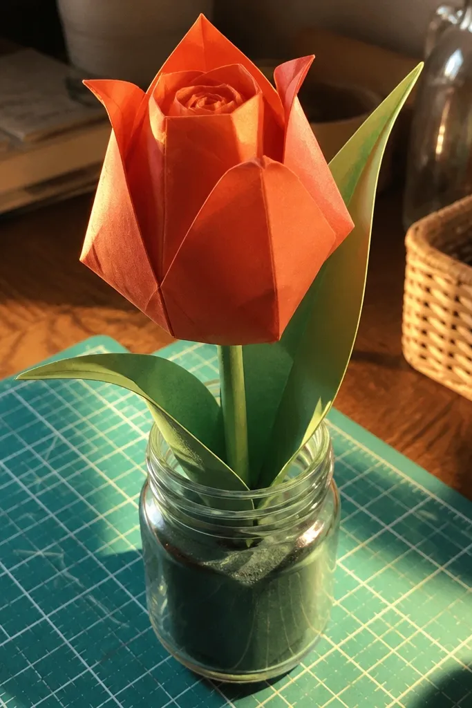 Orange tulip origami flower with rolled center and curled petals