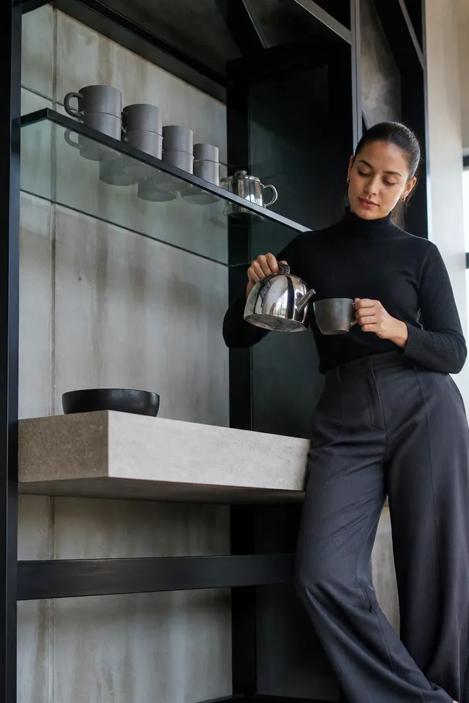 Black steel-framed corner coffee station with a floating glass shelf and minimal countertop
