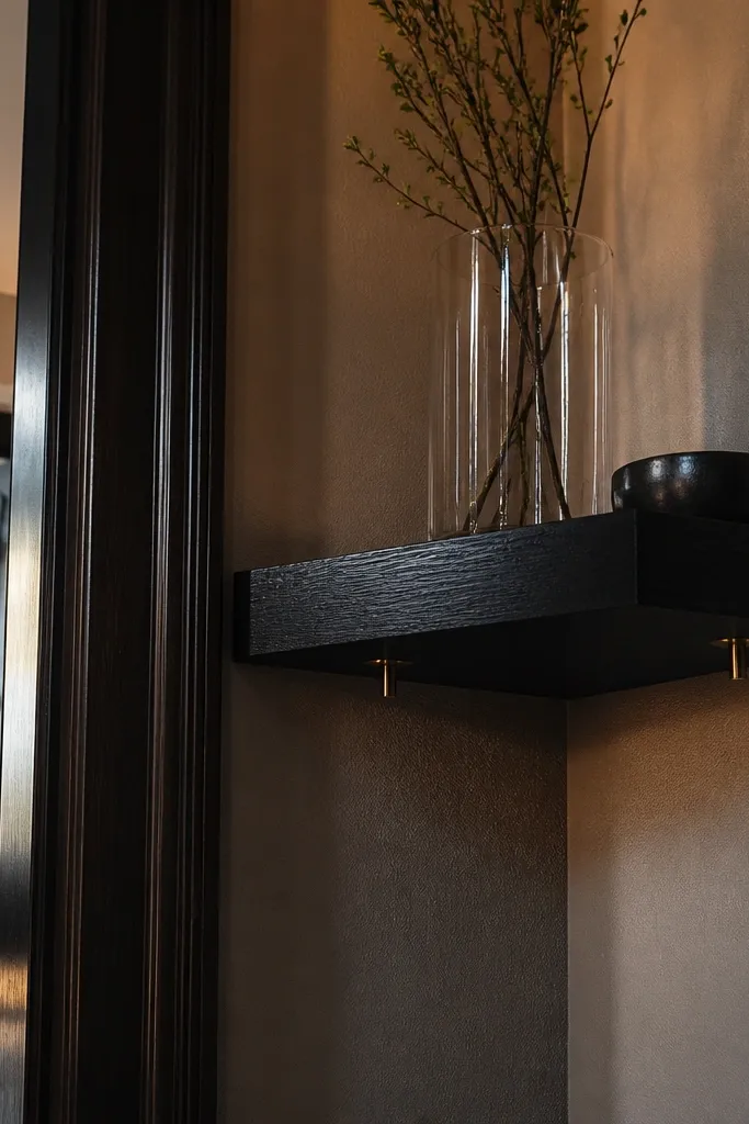 Black stained oak corner shelf with warm brass pins visible only at the underside.