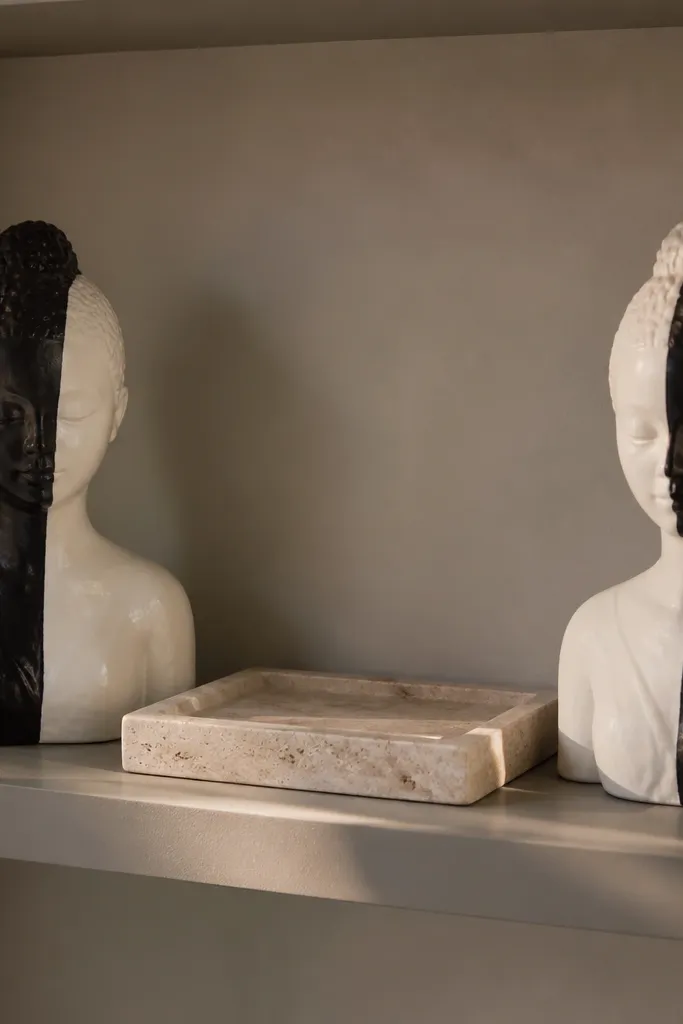 Black and white ceramic busts centered on a stone tray on built-in shelves