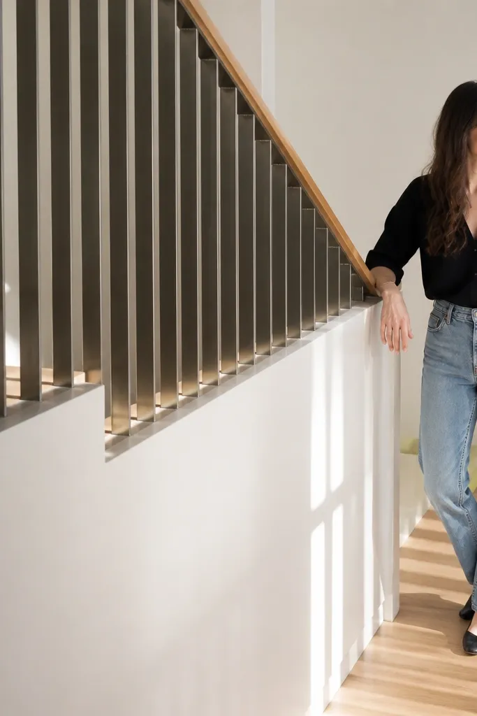 Matte white half wall with vertical metal slats and a light wood handrail