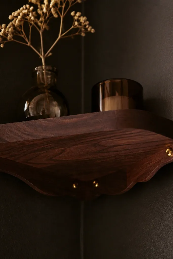 Smoked walnut corner shelf with scalloped underside and two brass pin supports