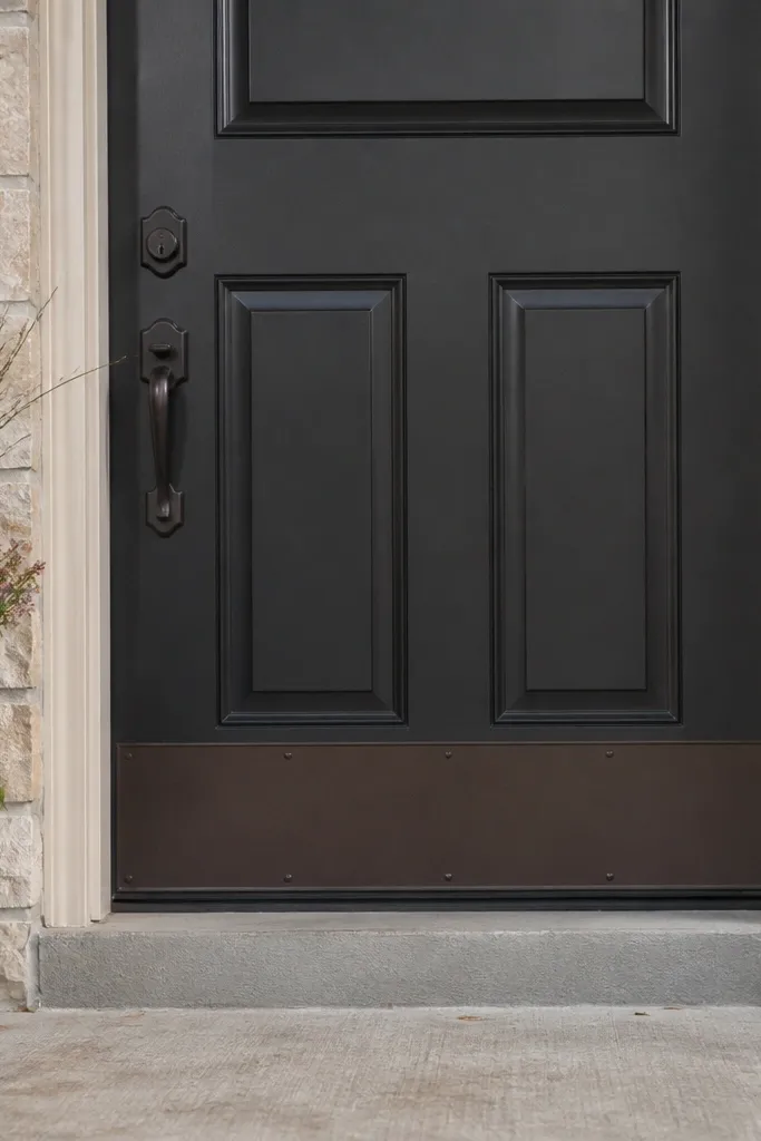 Front door with new lockset and a brushed metal kick plate