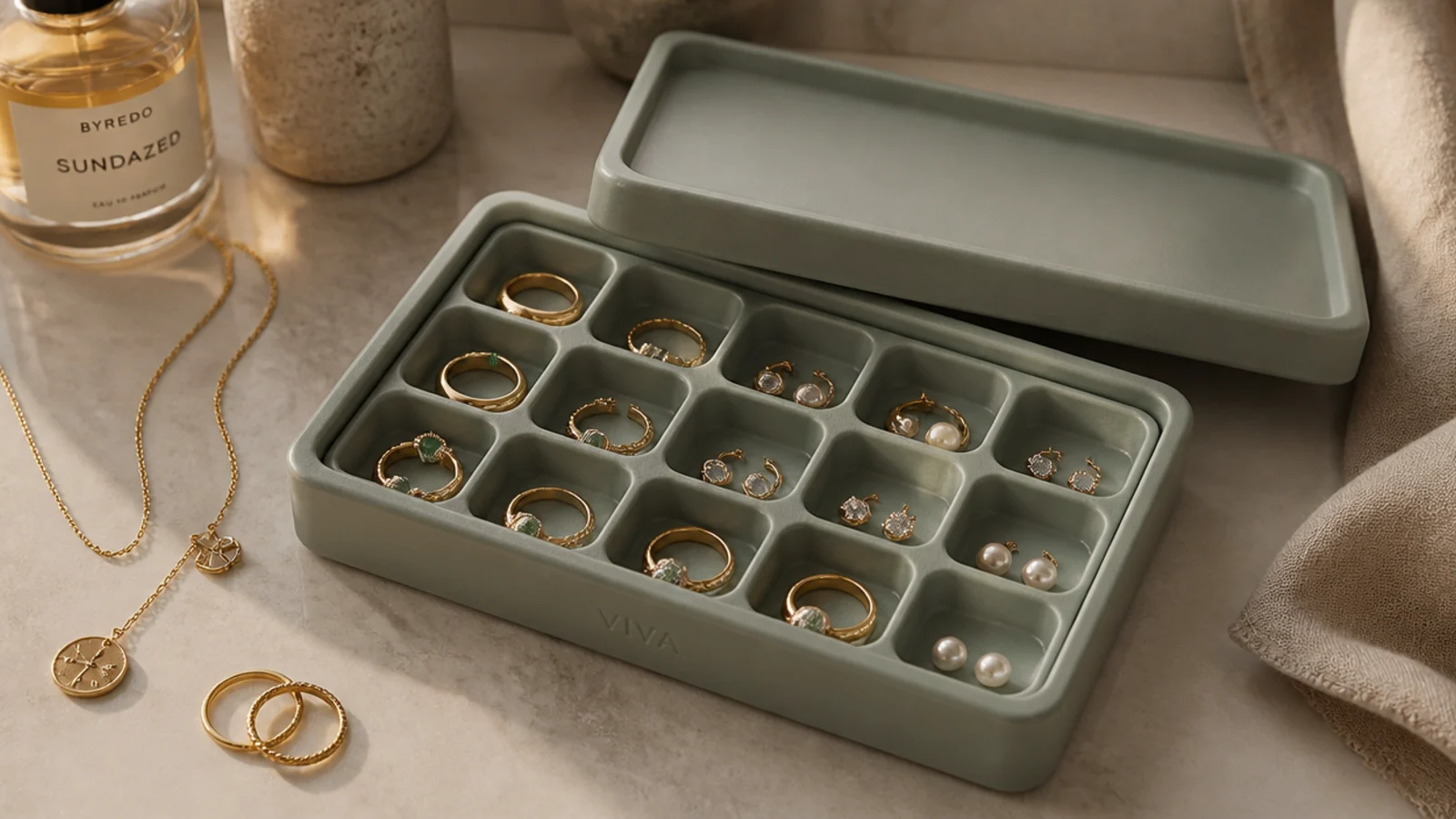 A shallow lidded box holding a silicone ice cube tray, each cell containing a separate ring or pair of studs.