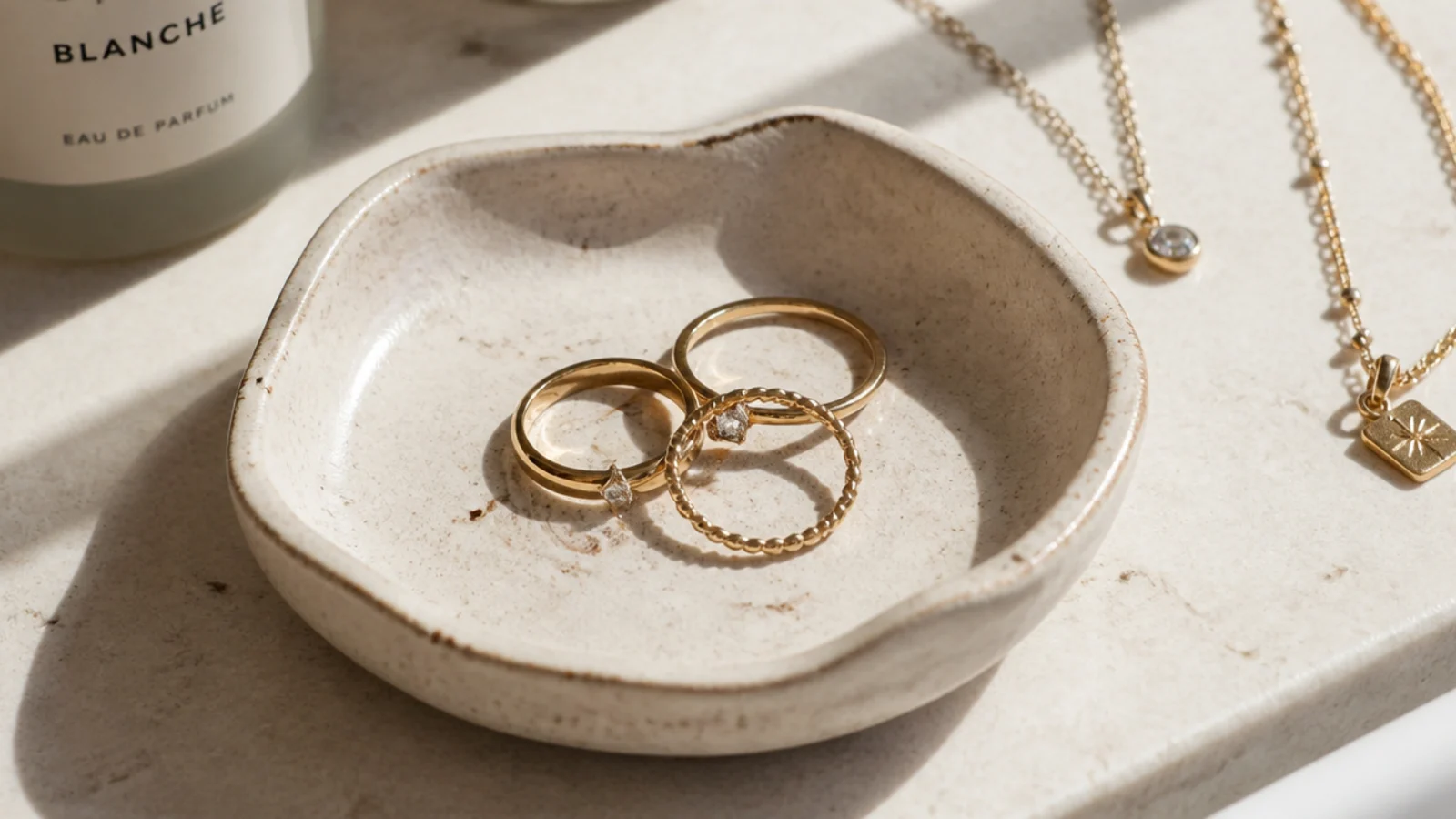 A small handmade clay ring dish on a bathroom sink ledge holding a few rings taken off before washing up.