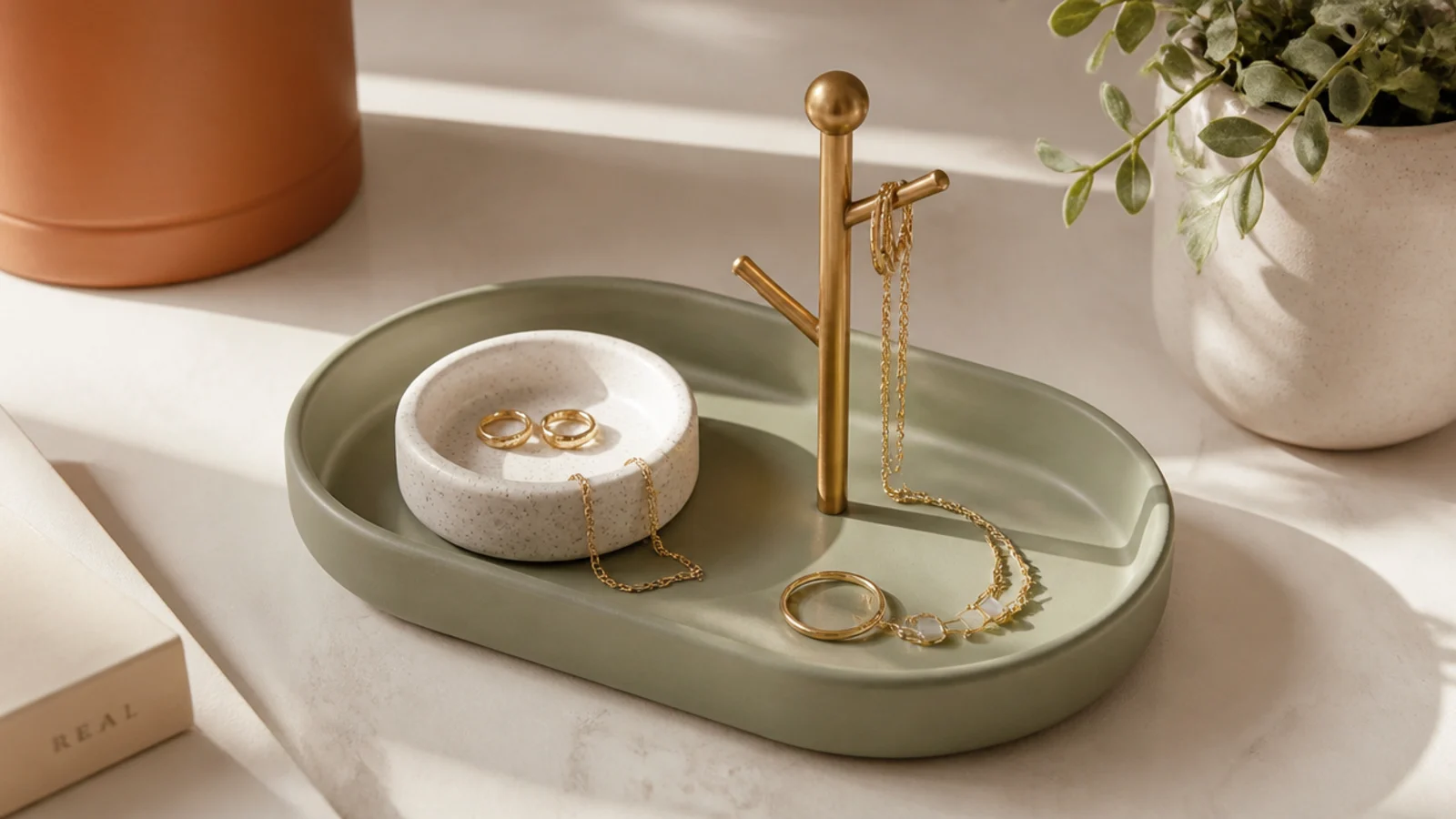 A small tray on a nightstand holding a ring dish and a tiny hook stand, catching the pieces taken off at bedtime.