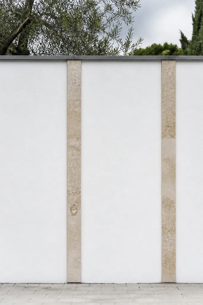 White rendered wall with narrow stone strip accents and a black cap