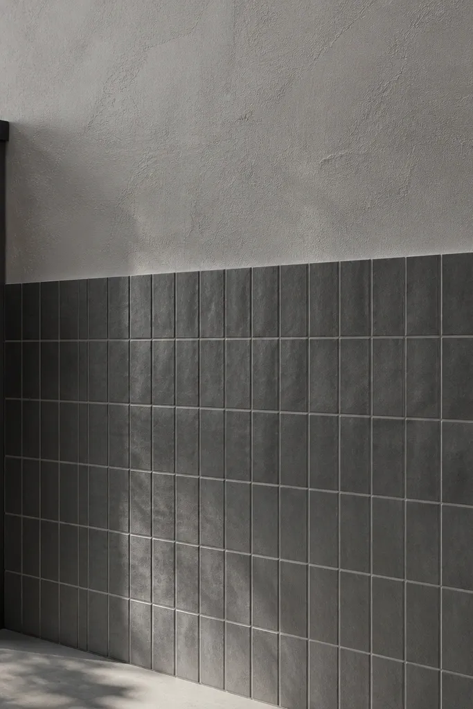 Lower half tiled in grey and upper half in textured plaster with a dark cap