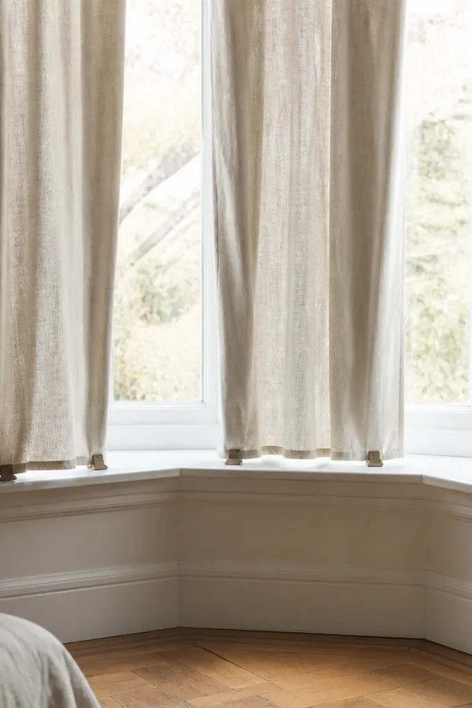Neutral linen-blend drapes with neat hems and clips on a bay window