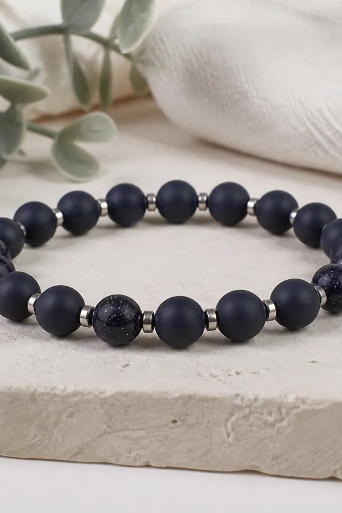A dark navy clay bracelet with 7mm beads; between each bead are thin silver micro spacer cylinders, and a few beads have speckled "star" flecks.