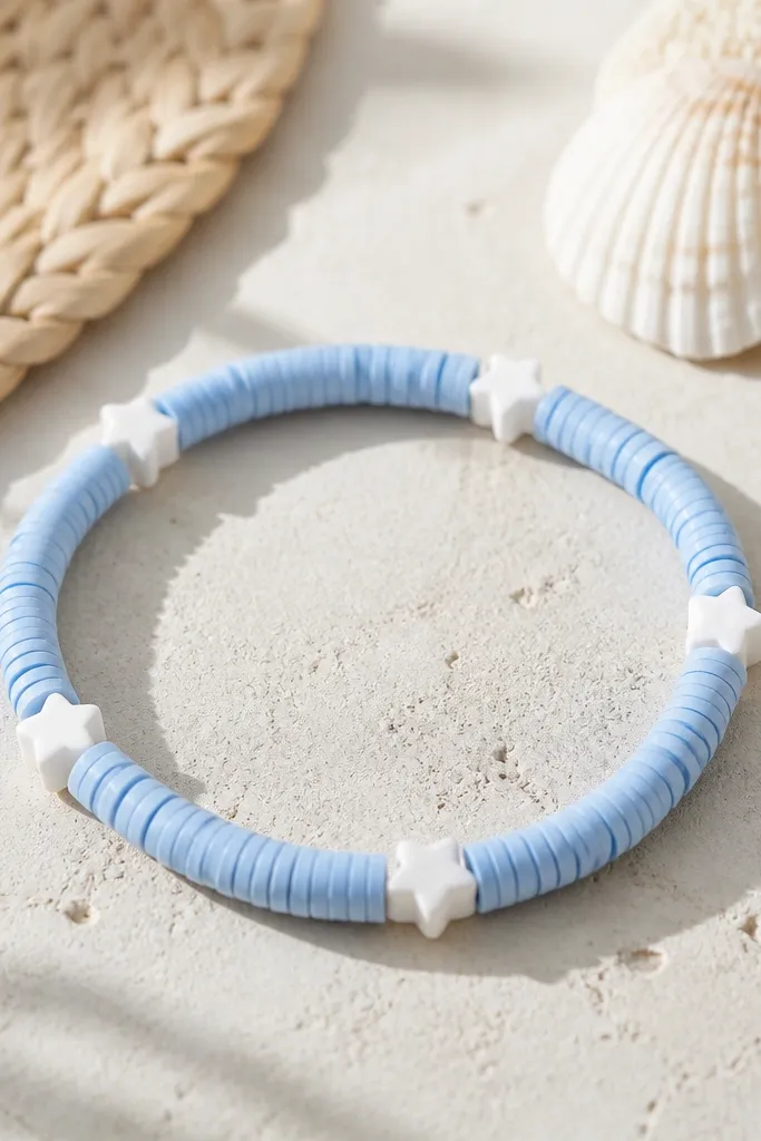 A summer bracelet featuring light blue clay beads and a few small white star-shaped clay beads spaced evenly; the star beads face outward.